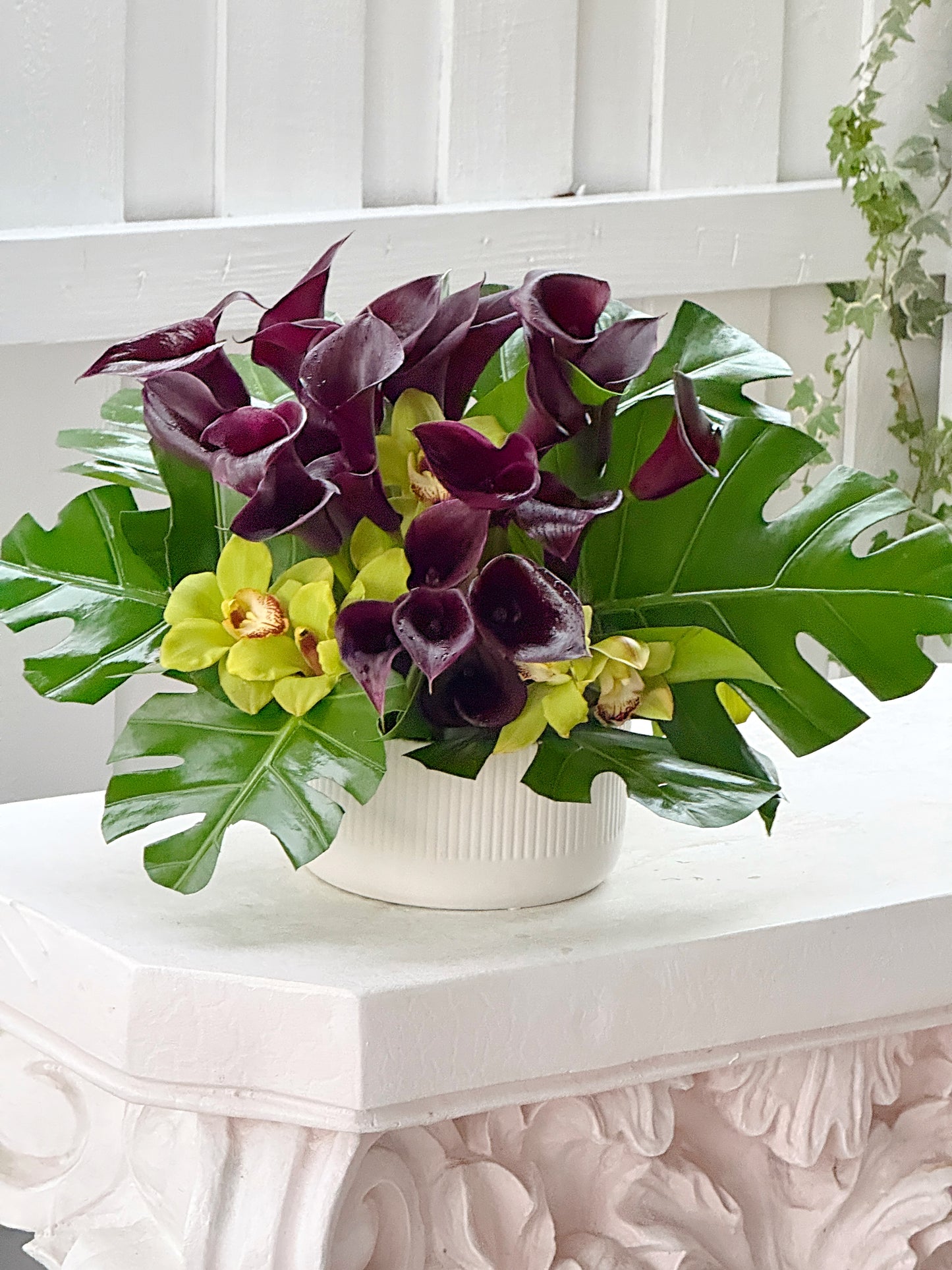 Purple Calla Lilies, Orchids Cymbidium & Monstera Leaves Flower Arrangement In A Ceramic Vase. - Miami Flower Store Same-Day Delivery Fort Lauderdale Brickell Aventura Las Olas Hallendale Beach Hollywood Sunny Isles
